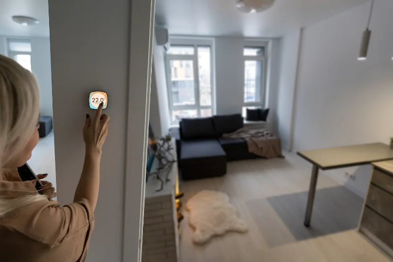 Woman adjusting thermostat at home.