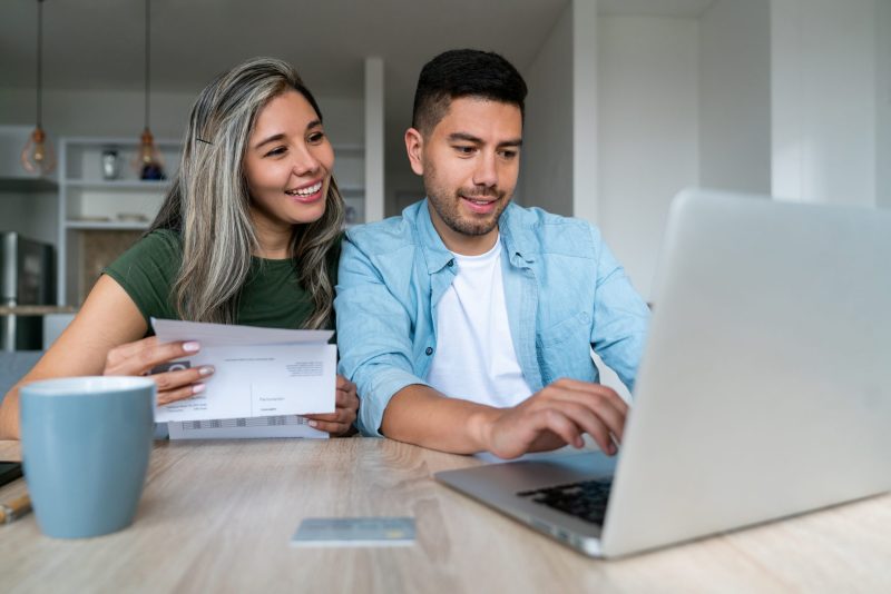 Happy couple at home in front of the computer.